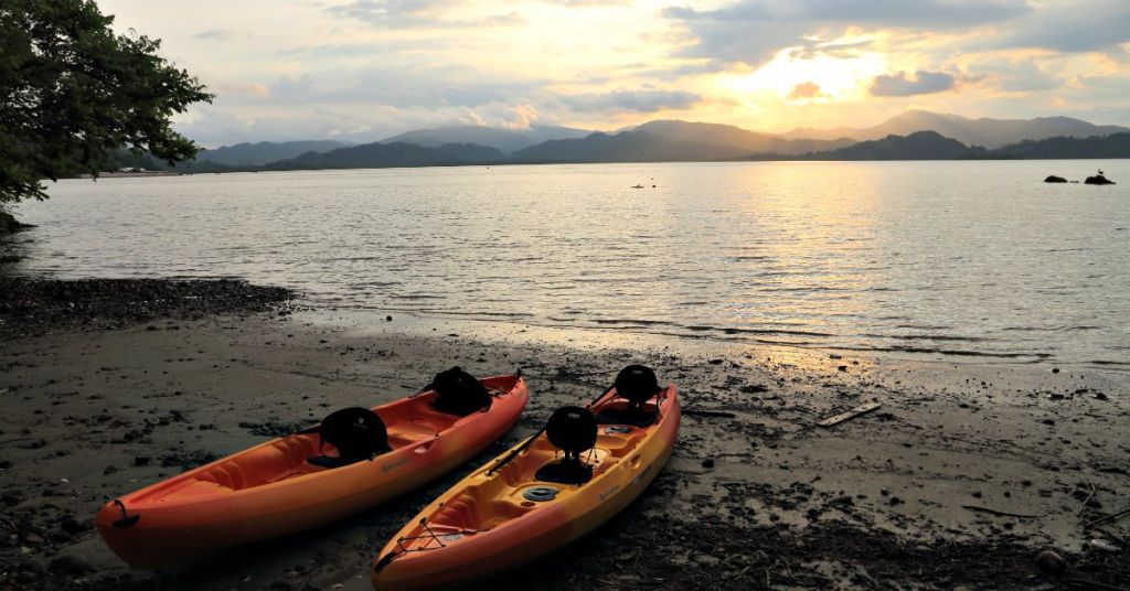 Two orange kayaks on bay in Costa Rica at sunset.