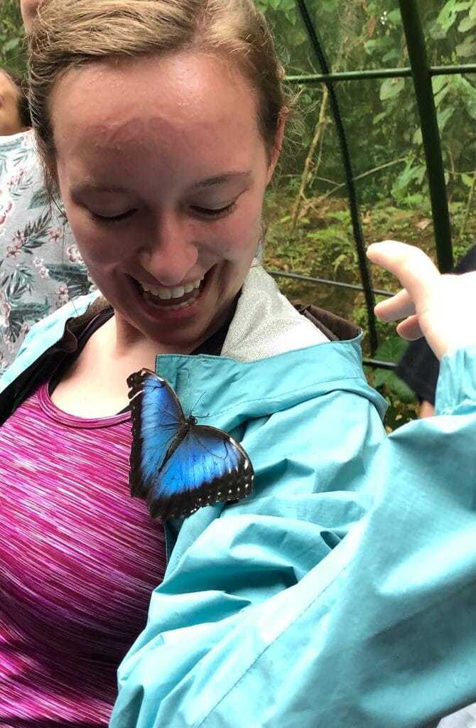 Young woman with a morpho butterfly perched on her jacket.