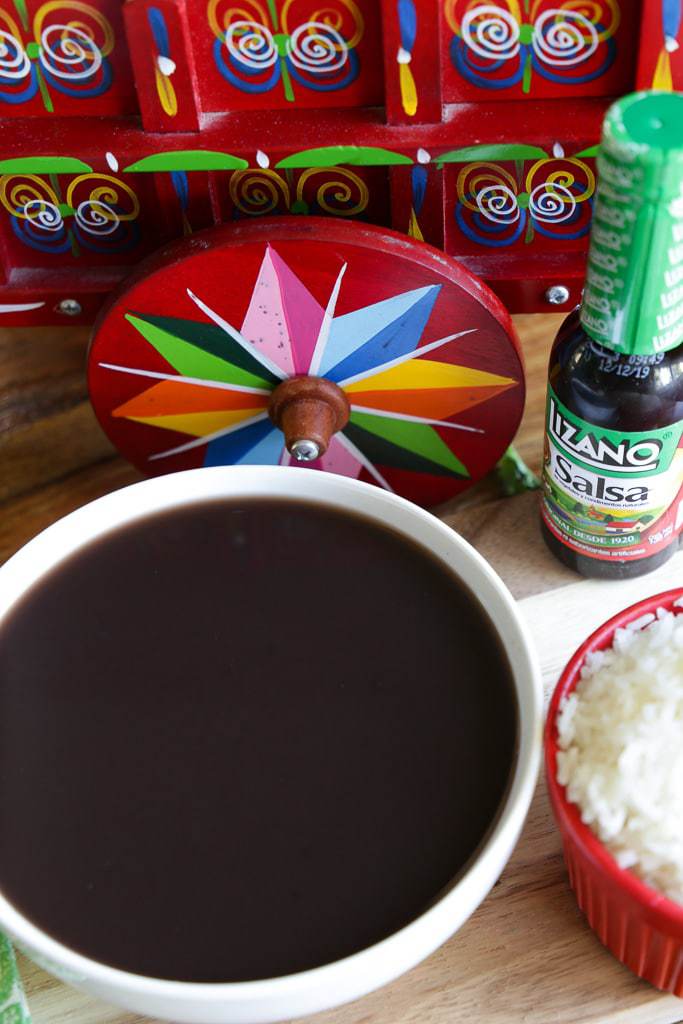 black bean soup with salsa lizano and red costa rican ox cart in background