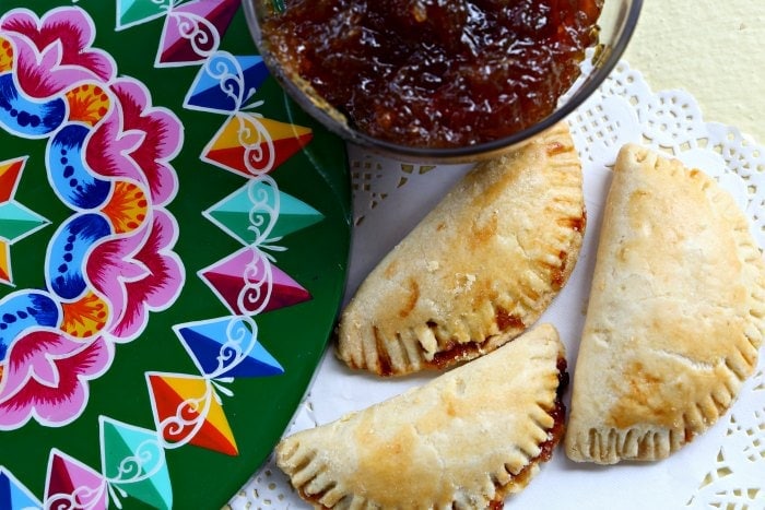Three baked chiverre empanadas arranged on a doily.