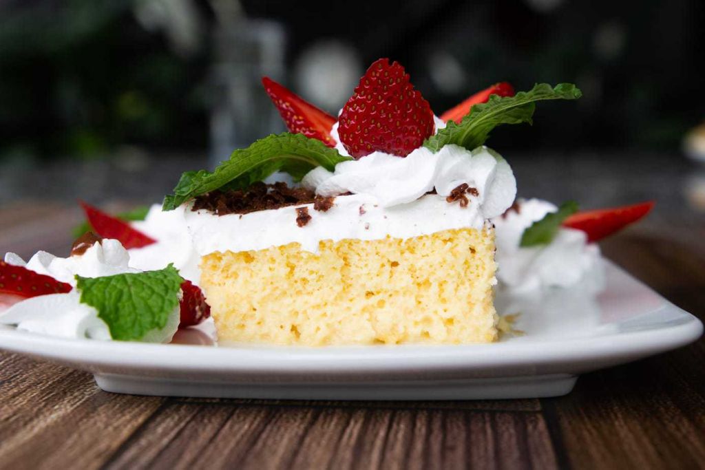 Cross section of Costa Rican moist cake topped with strawberries and mint.