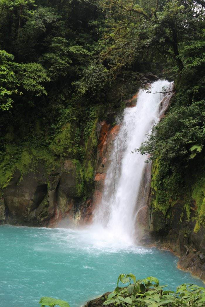 Waterfall cascading into blue river.