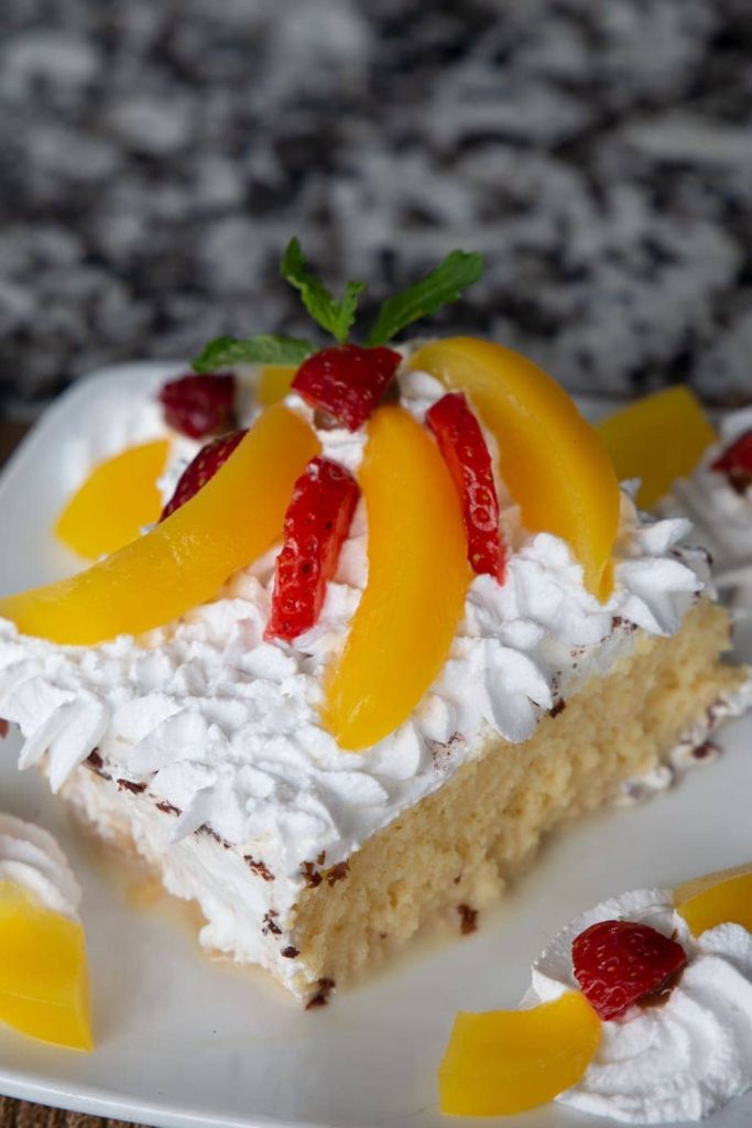 tres leches cake topped with peach slices and strawberries