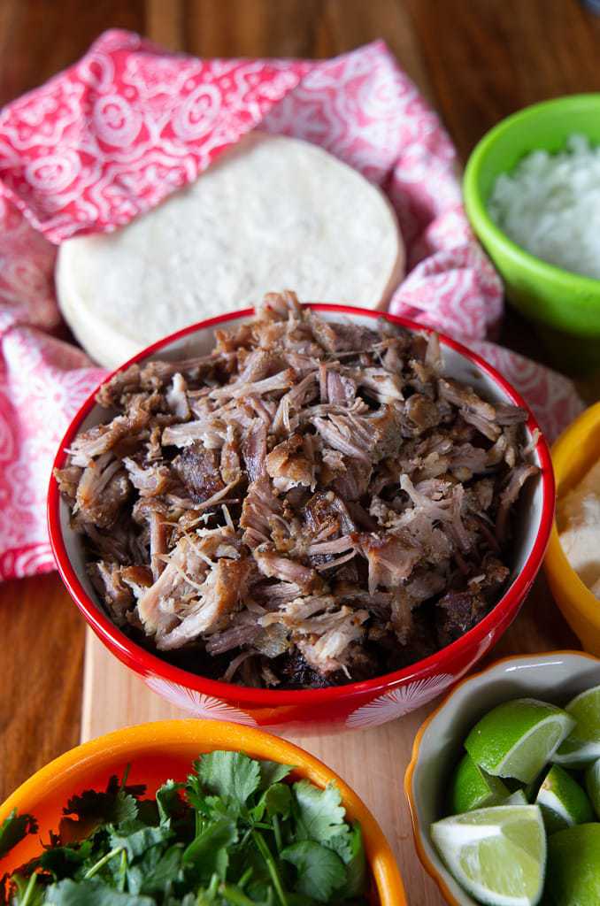Mexican shredded pork in bowl with white corn tortillas