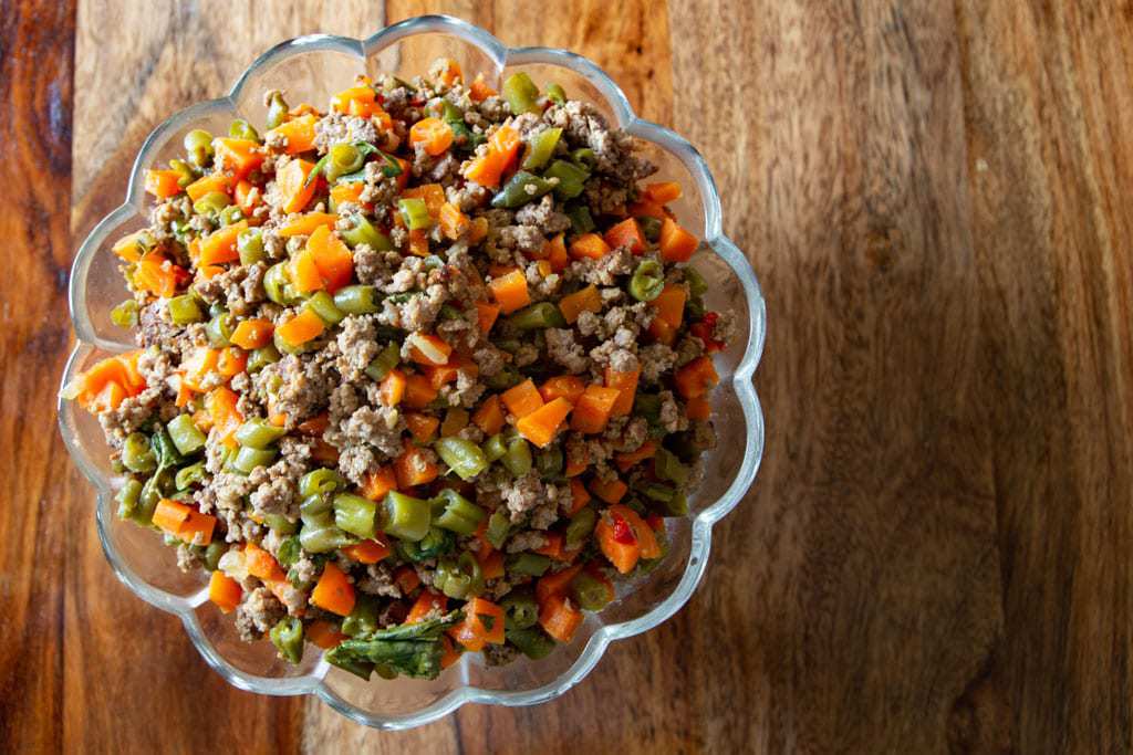 picadillo de vainica in scalloped edge glass bowl on table.